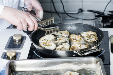 On a black skillet cooked pieces of fish, sturgeon.