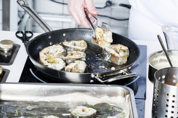 On a black skillet cooked pieces of fish, sturgeon.