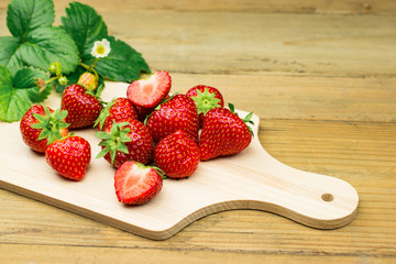 Fresh sweet strawberries from the field. Presented on wooden cutting board.