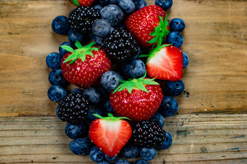 Mixed berries: fresh strawberries,blueberries and blackberries on wooden background.