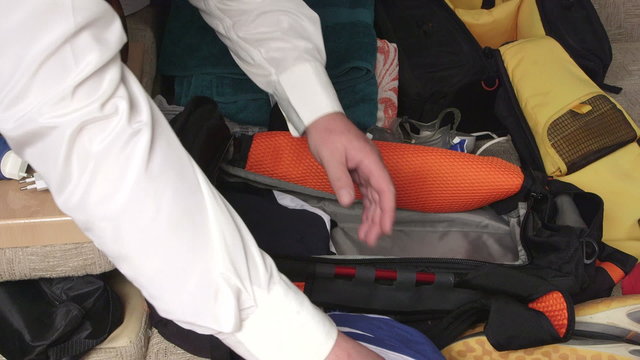 Man traveler packing clothes in travel bag on the bed prepping for trip