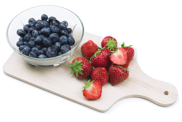 Isolated blueberries and strawberries on wooden cutting board.
Kitchen concept