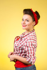 Beautiful young woman with pin-up make-up and hairstyle posing over pink background
