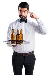 Waiter with beer bottles on the tray thinking