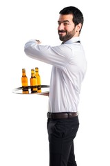 Waiter with beer bottles on the tray pointing back