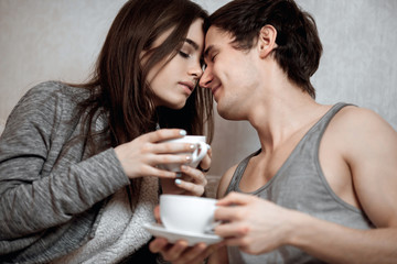 Young beautiful pair of lovers drink tea (coffee) in bed