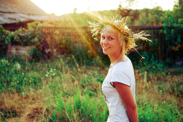 Portrait of a romantic smiling young woman in a circlet of flowers outdoors.