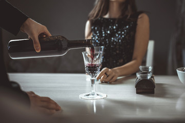 Beautiful young couple with glasses of red wine in luxury restaurant
