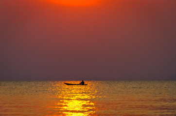Fisherman in a boat in the sea at sunset background
