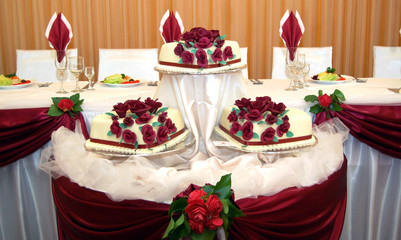 white wedding cake with red roses on a wedding table