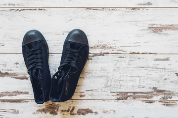 Pair of black trainers on wooden floor top view