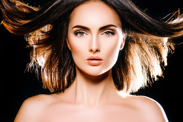 The girl brunette model with flying hair in studio on a black background