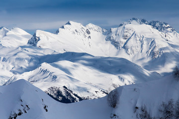 top view to Caucasian mountains covered by snow and cloud shadows  