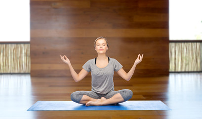 woman making yoga meditation in lotus pose on mat