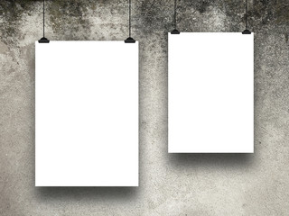 Close-up of two hanged asymmetrical paper sheet frames with clips on grey weathered concrete wall background