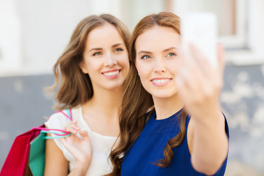 happy women with shopping bags and smartphone