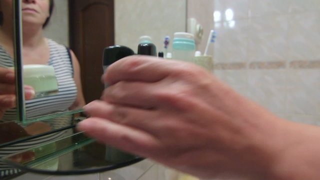 Woman protects skin of hands when doing household chores applying moisturizer hand lotion in the bathroom