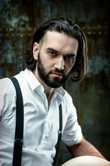 Handsome man posing in white shirt on dark metal wall background
