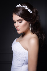 beautiful gentle girl groom in a wedding dress with hairstyle and make-up, hair decorated with a wreath of flowers