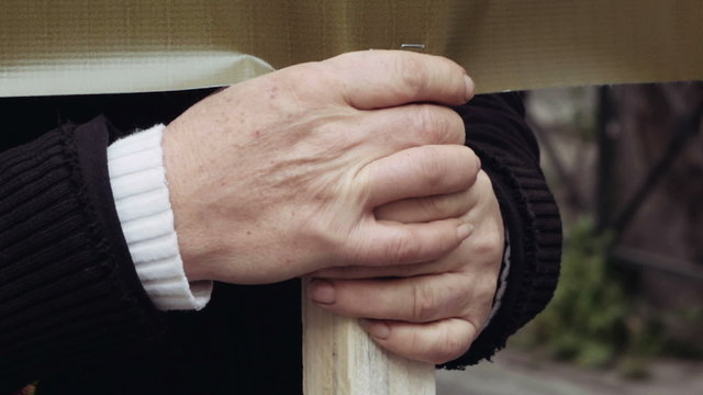 The hand of an elder retired woman holding a sing in protest in the streets