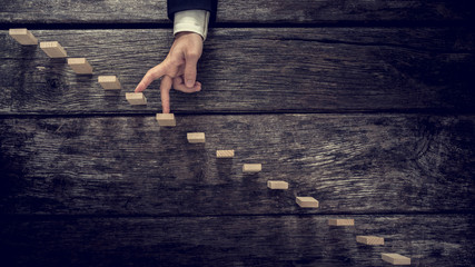 Businessman walking his fingers up wooden steps