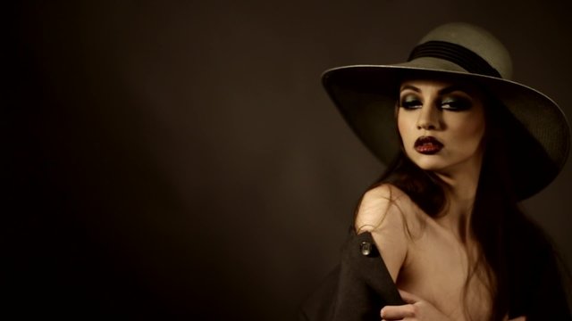 attractive girl in a hat with naked shoulders on a photo shoot in the studio