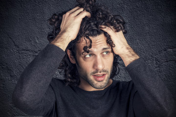 Portrait of desperate young attractive man with curly hair
