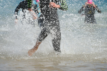 Triathletes running out of the water on triathlon race.