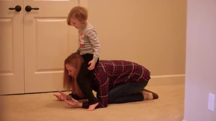 A little girl climbs on her mom to ride on her shoulders at home, slow motion