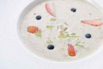 Bowl of delicious breakfast oat and mixed with fruit served in a white ceramic bowl for a healthy nutritious meal
