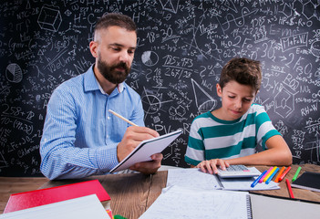 Hipster teacher with his student with calculator, big blackboard