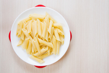 Penne pasta on a white round plate on the table