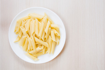 Penne pasta on a white round plate on the table