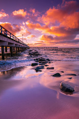 Obraz premium Pier and sea at pink sunset