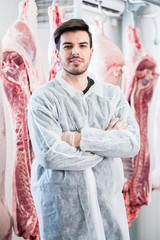 Arbeiter im Schlachthoft steht vor geschlachteten Tieren, die zur Fleischverarbeitung bereit stehen