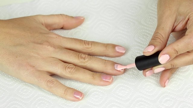 Manicure in process - painting gel polish of pink color on female nails 