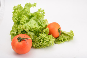 Closeup photo of fresh tomatoes lying on lettuce leaves on white