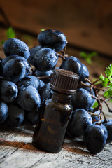 Grape seed oil in brown bottle, bunch of grapes, vine at the old