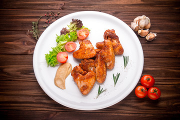 Grilled chicken wings with vegatables and seasoning on a wooden