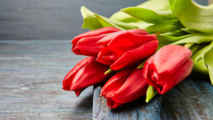 Red tulips on a dark wooden table