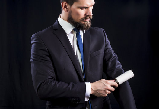 Elegant bearded man in dark suit holds sticky brush for cleaning clothes from dust.