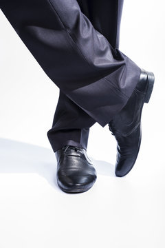 Man's legs in classic suit and leather shoes on white background.