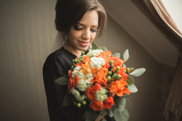 Luxury bride in black robe posing while preparing for the wedding ceremony