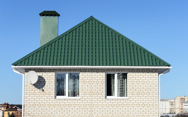 Fototapeta na wymiar Green roof of white brick house