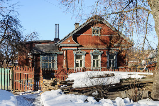 Old wooden house with pile of wood in winter