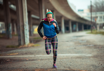 Female in sports wear jogging  in city environment.
