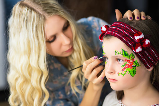 Woman painting the face of a little girl