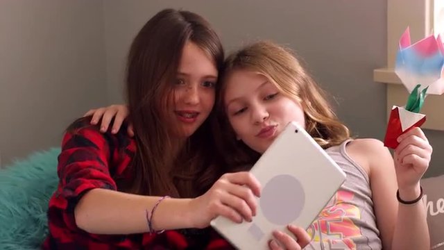 Preteen friends taking selfies with a tablet at home