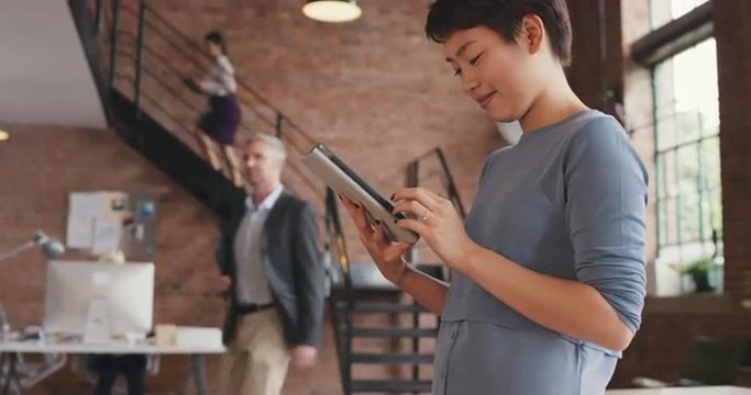 Stylish Asian Business woman using digital tablet in boardroom