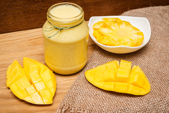 Smoothies mango and yogurt in a glass jar on wooden background.